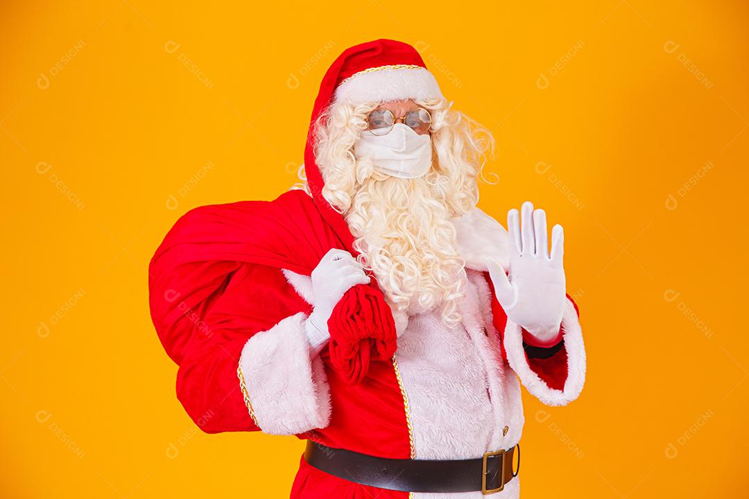 Real Papai Noel em fundo amarelo, usando máscara protetora contra o covid19. Natal com distanciamento social. Covid-19