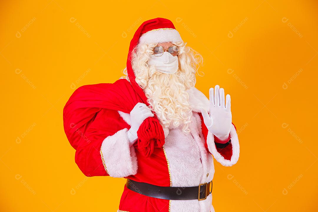 Real Papai Noel em fundo amarelo, usando máscara protetora contra o covid19. Natal com distanciamento social. Covid-19