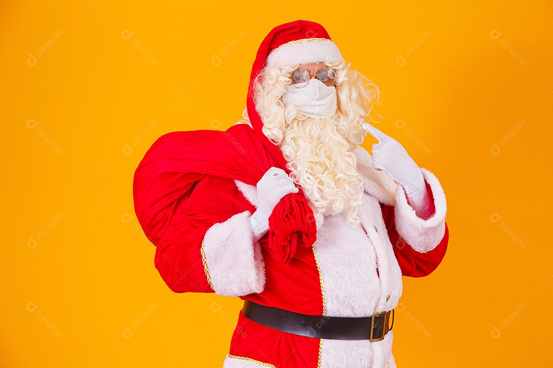 Real Papai Noel em fundo amarelo, usando máscara protetora contra o covid19. Natal com distanciamento social. Covid-19