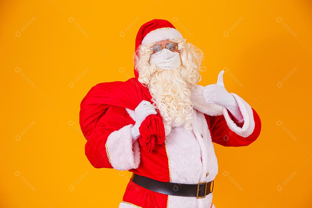 Real Papai Noel em fundo amarelo, usando máscara protetora contra o covid19. Natal com distanciamento social. Covid-19