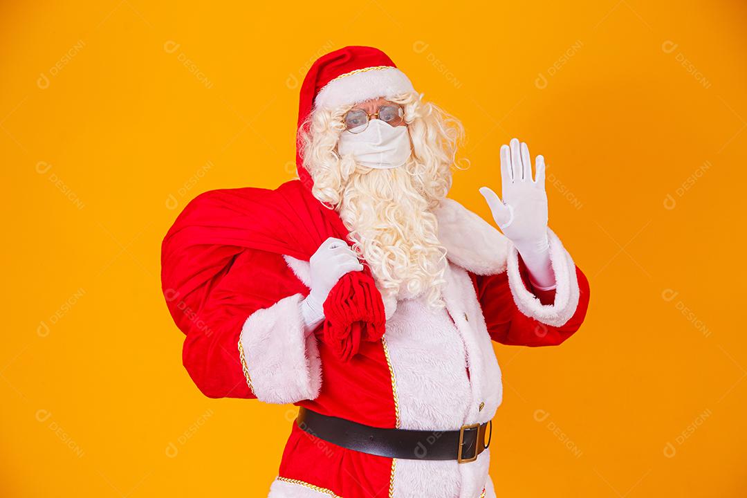 Real Papai Noel em fundo amarelo, usando máscara protetora contra o covid19. Natal com distanciamento social. Covid-19