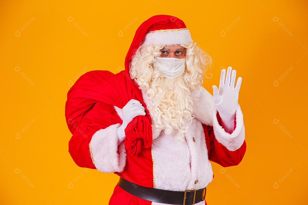 Real Papai Noel em fundo amarelo, usando máscara protetora contra o covid19. Natal com distanciamento social. Covid-19