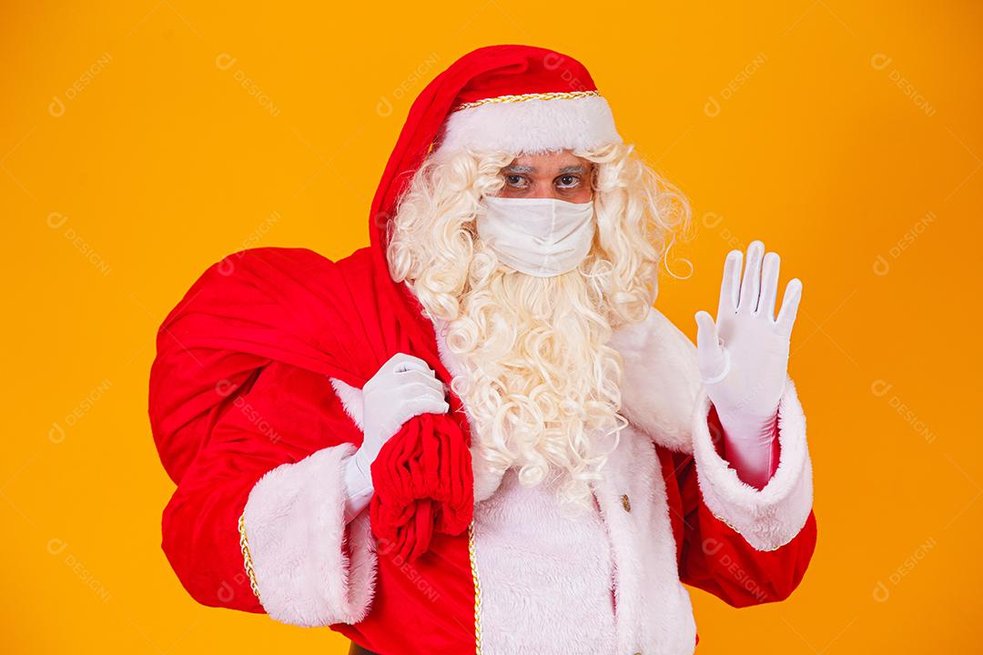 Real Papai Noel em fundo amarelo, usando máscara protetora contra o covid19. Natal com distanciamento social. Covid-19