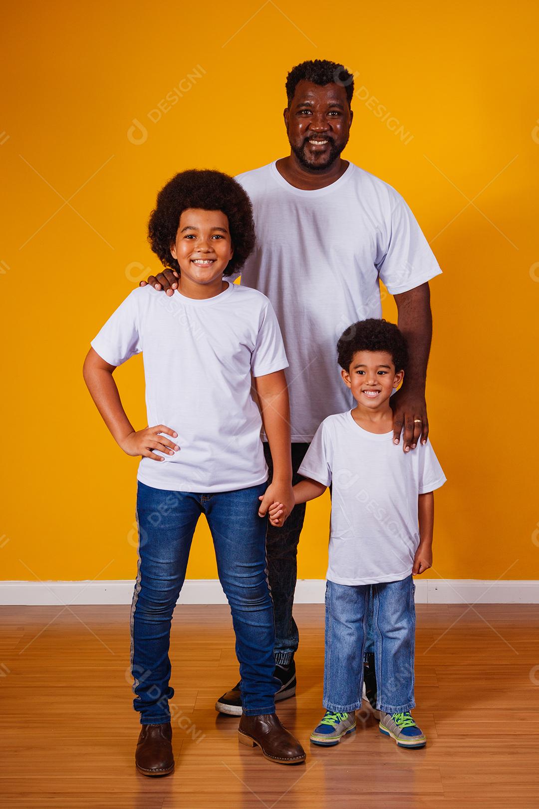 Retrato de pai afro-americano com seus filhos negros sobre fundo amarelo. Dia dos Pais