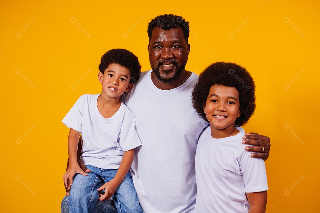Retrato de pai afro-americano com seus filhos negros sobre fundo amarelo. Dia dos Pais