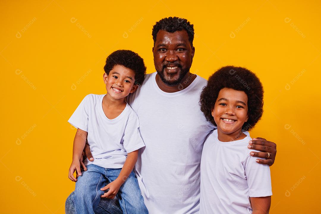 Retrato de pai afro-americano com seus filhos negros sobre fundo amarelo. Dia dos Pais