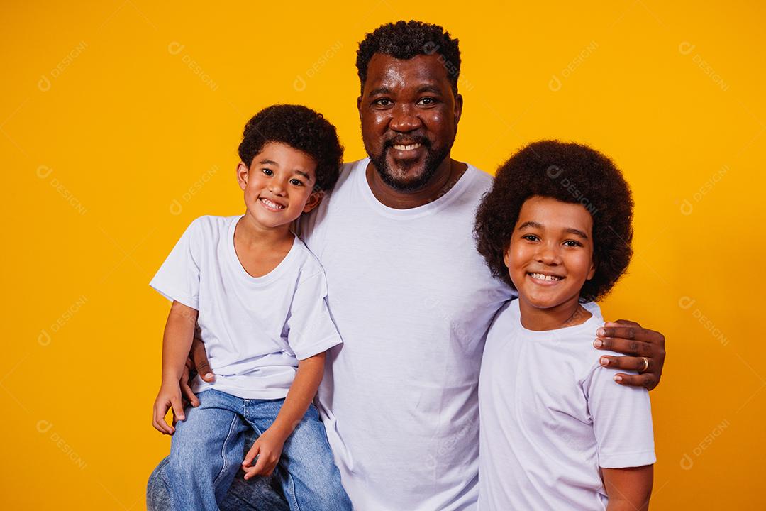 Retrato de pai afro-americano com seus filhos negros sobre fundo amarelo. Dia dos Pais