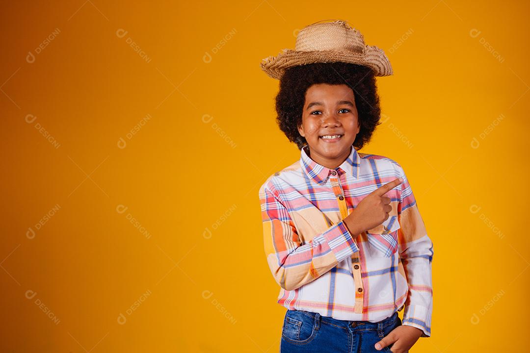 Retrato de um menino afro vestindo roupas típicas para a Festa Junina