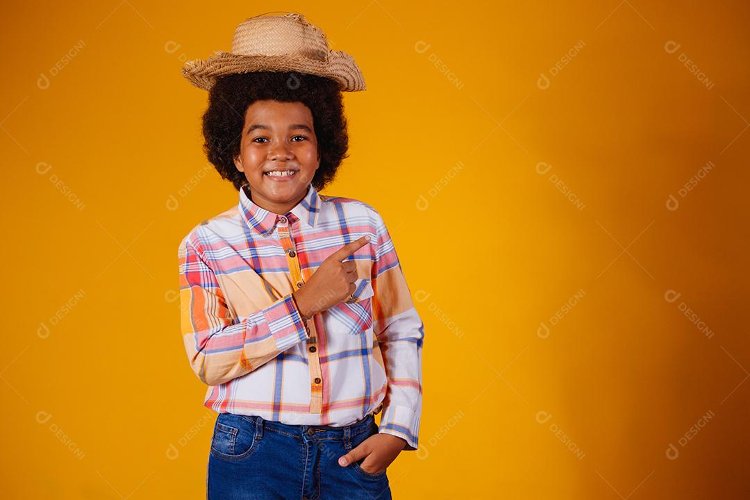 Retrato de um menino afro vestindo roupas típicas para a Festa Junina