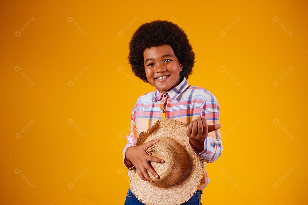 Retrato de um menino afro vestindo roupas típicas para a Festa Junina