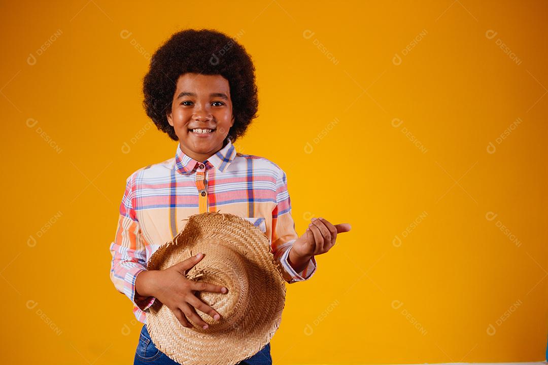 Retrato de um menino afro vestindo roupas típicas para a Festa Junina