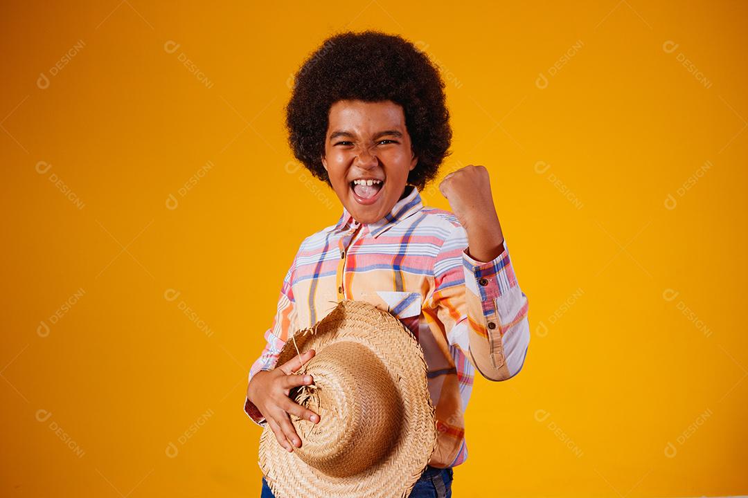 Retrato de um menino afro vestindo roupas típicas para a Festa Junina