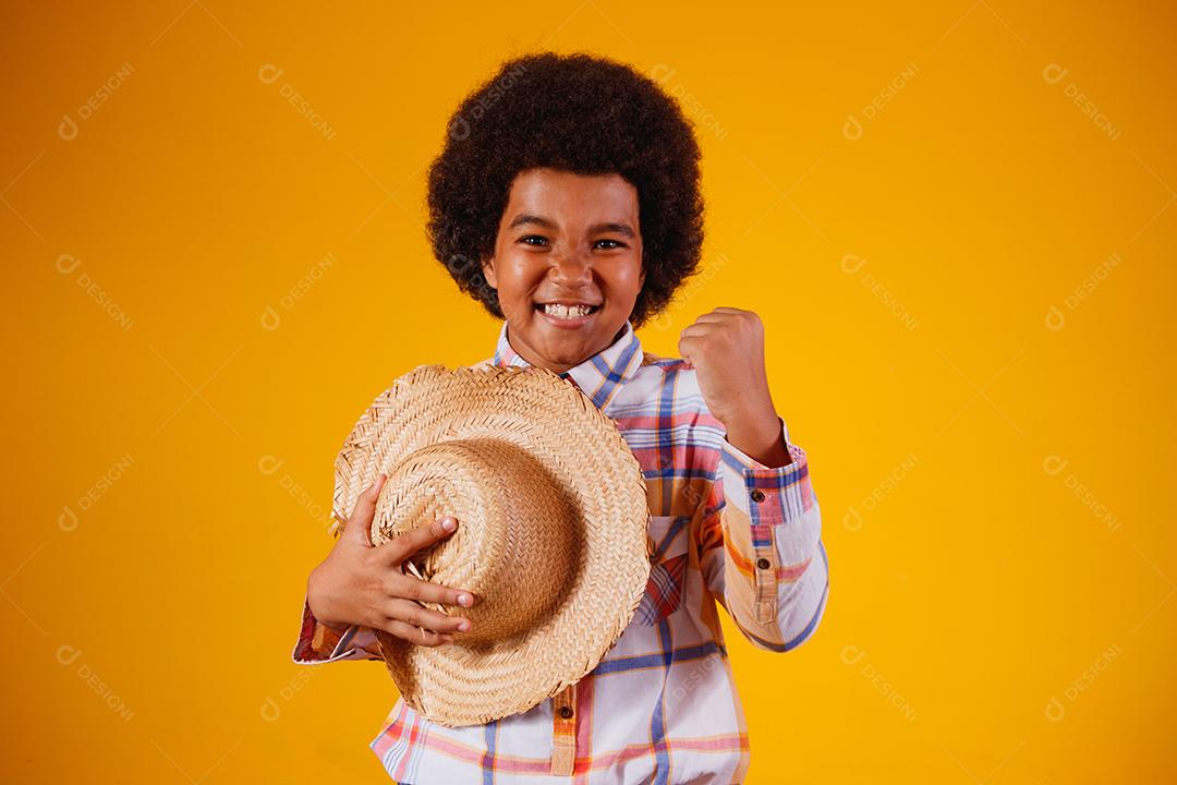 Retrato de um menino afro vestindo roupas típicas para a Festa Junina