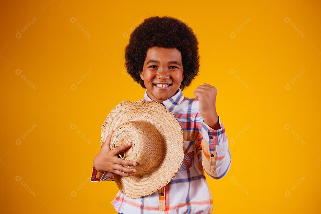 Retrato de um menino afro vestindo roupas típicas para a Festa Junina