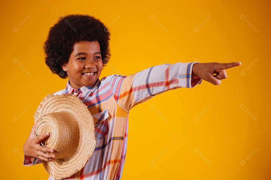 Retrato de um menino afro vestindo roupas típicas para a Festa Junina