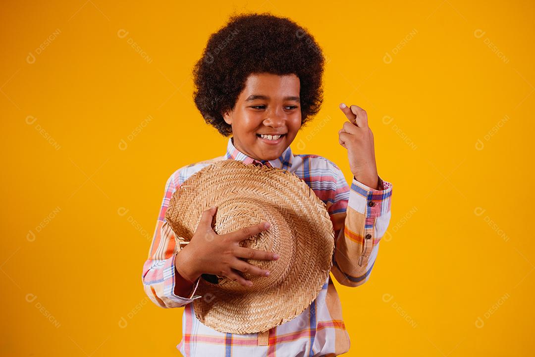 Retrato de um menino afro vestindo roupas típicas para a Festa Junina