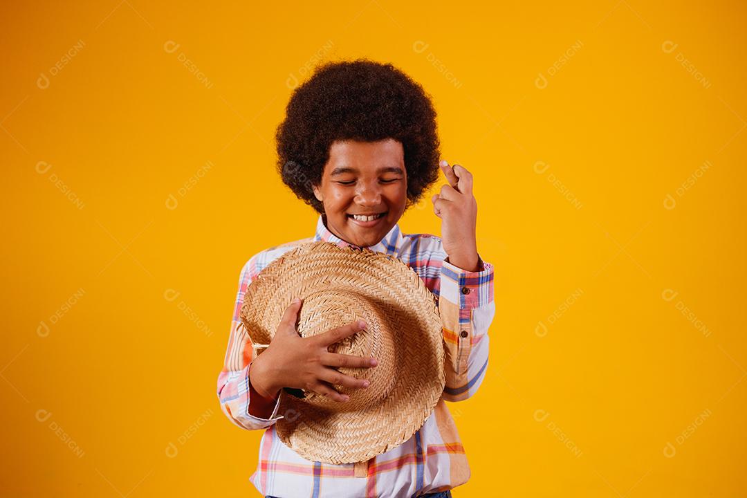 Retrato de um menino afro vestindo roupas típicas para a Festa Junina