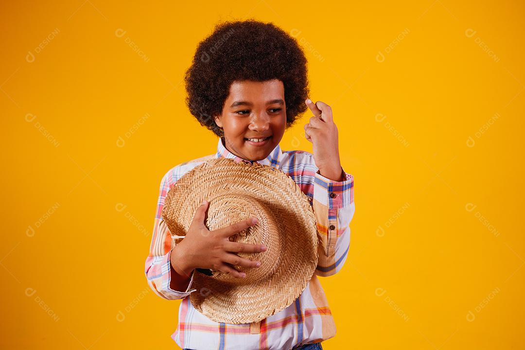 Retrato de um menino afro vestindo roupas típicas para a Festa Junina