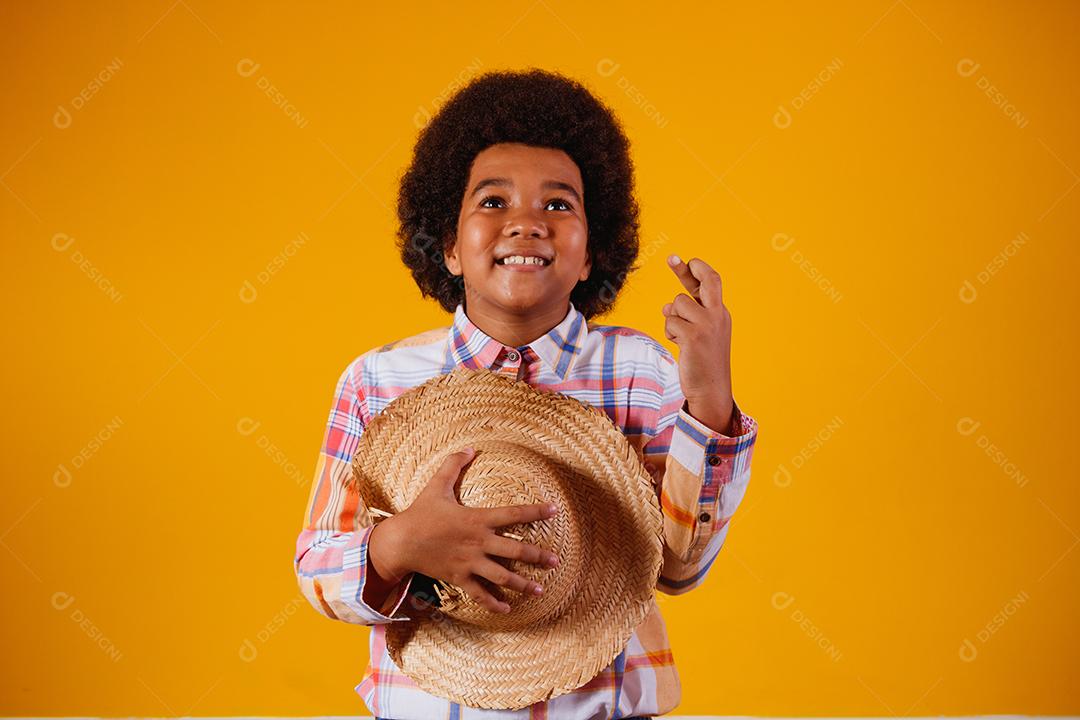 Retrato de um menino afro vestindo roupas típicas para a Festa Junina