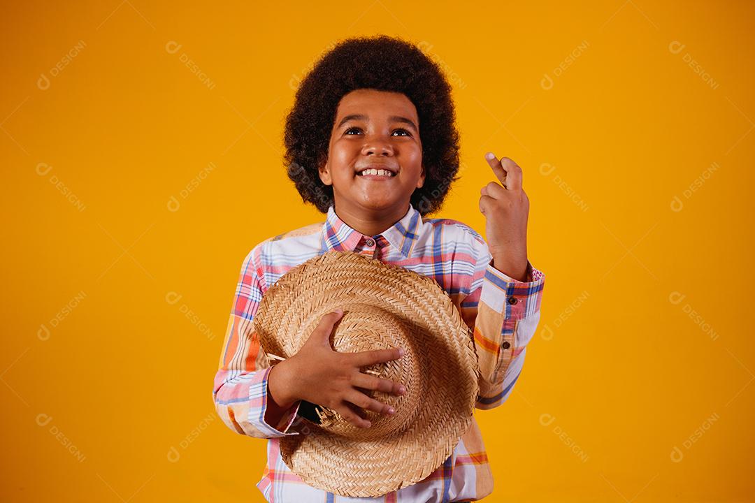 Retrato de um menino afro vestindo roupas típicas para a Festa Junina