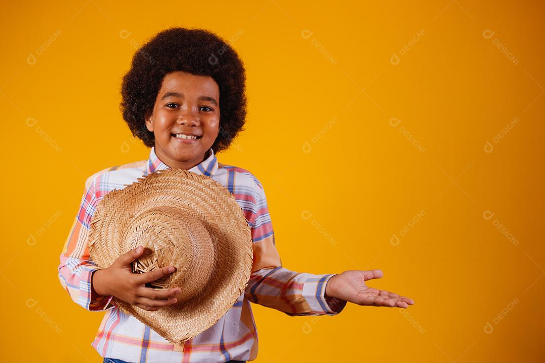 Retrato de um menino afro vestindo roupas típicas para a Festa Junina