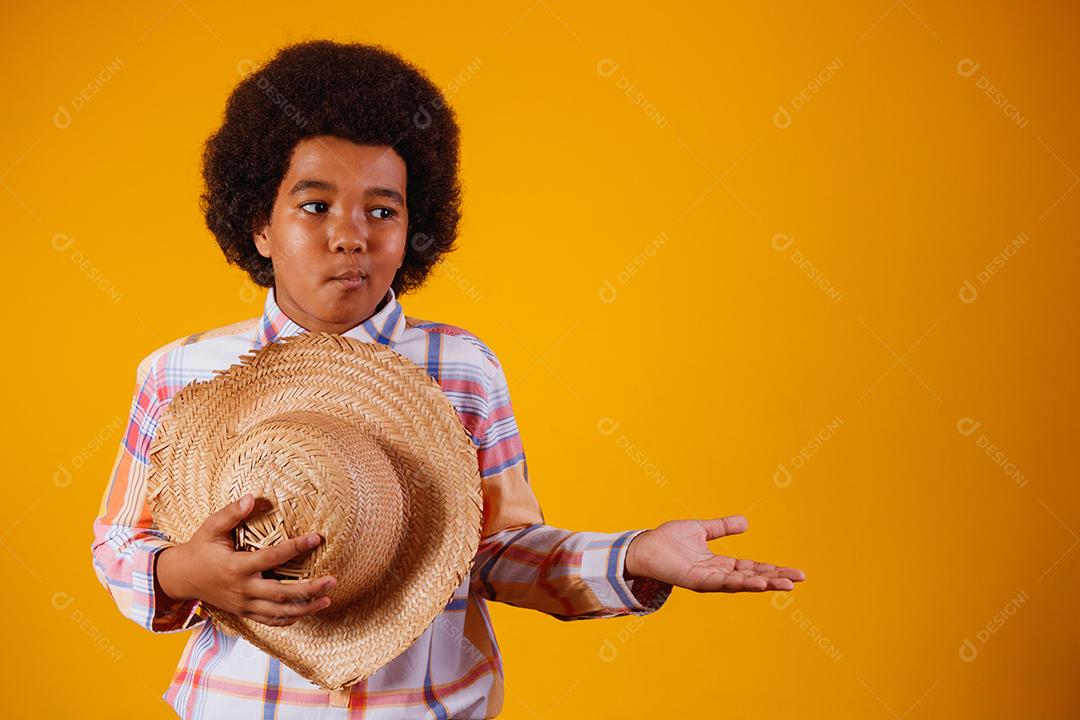 Retrato de um menino afro vestindo roupas típicas para a Festa Junina