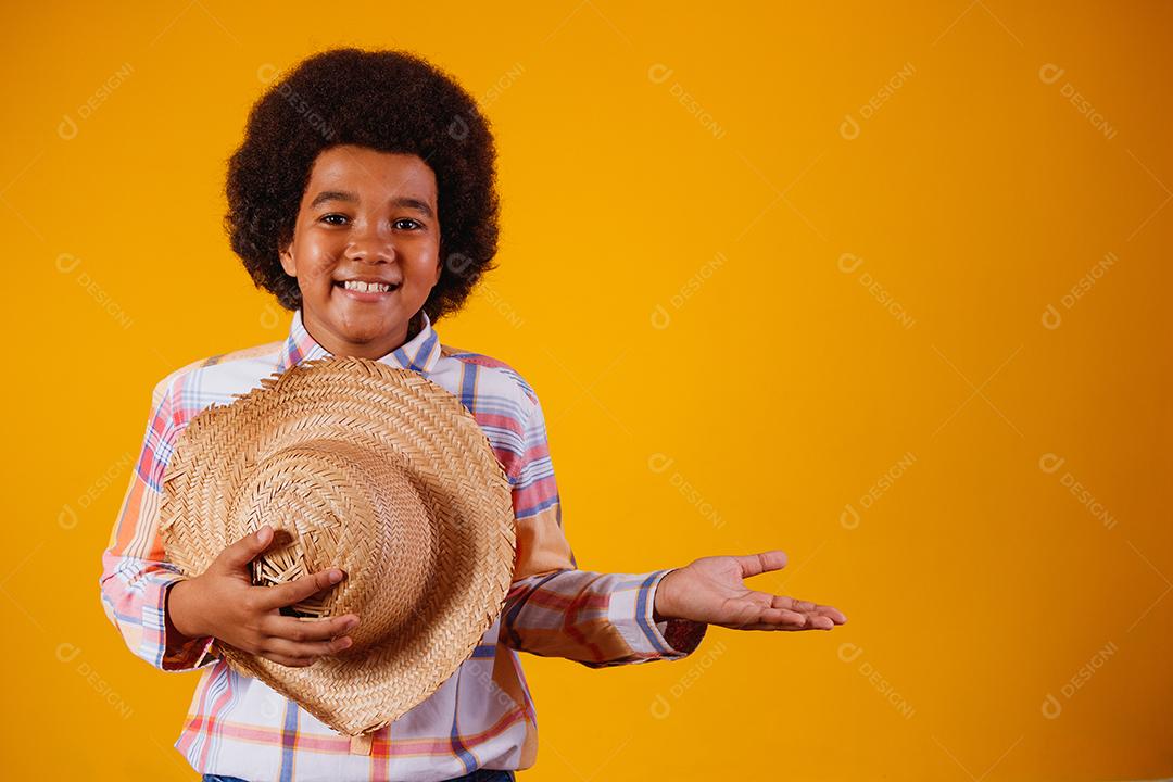 Retrato de um menino afro vestindo roupas típicas para a Festa Junina
