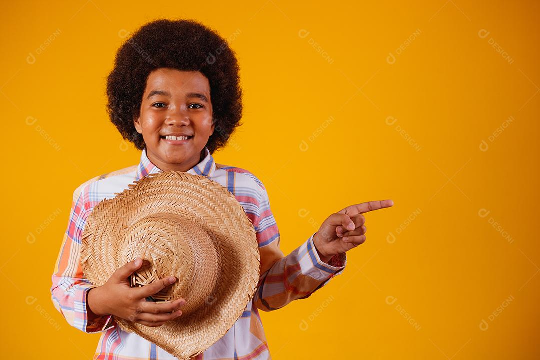 Retrato de um menino afro vestindo roupas típicas para a Festa Junina