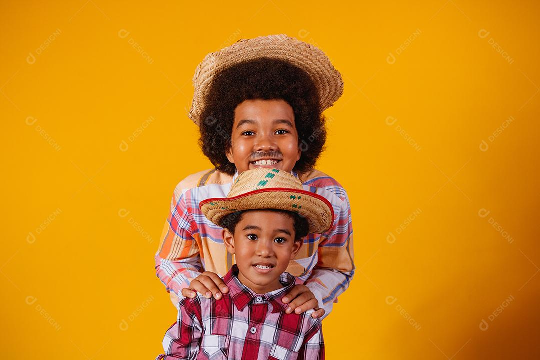 Irmãos afro vestidos com roupas de festa junina