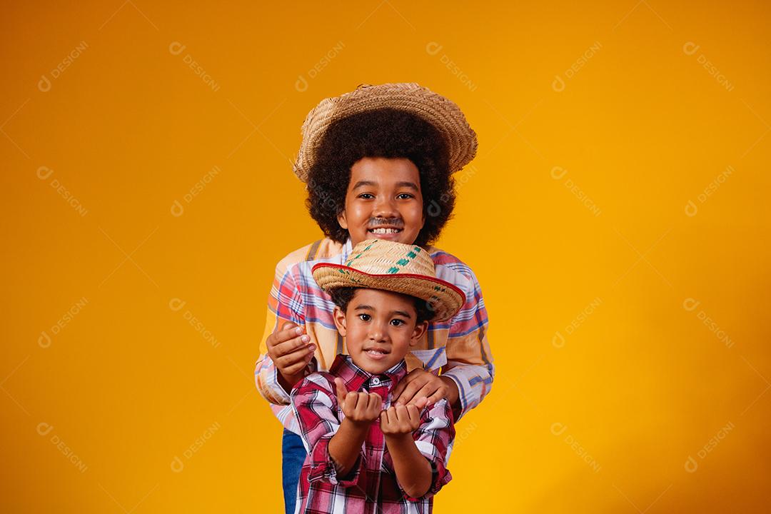 Irmãos afro vestidos com roupas de festa junina