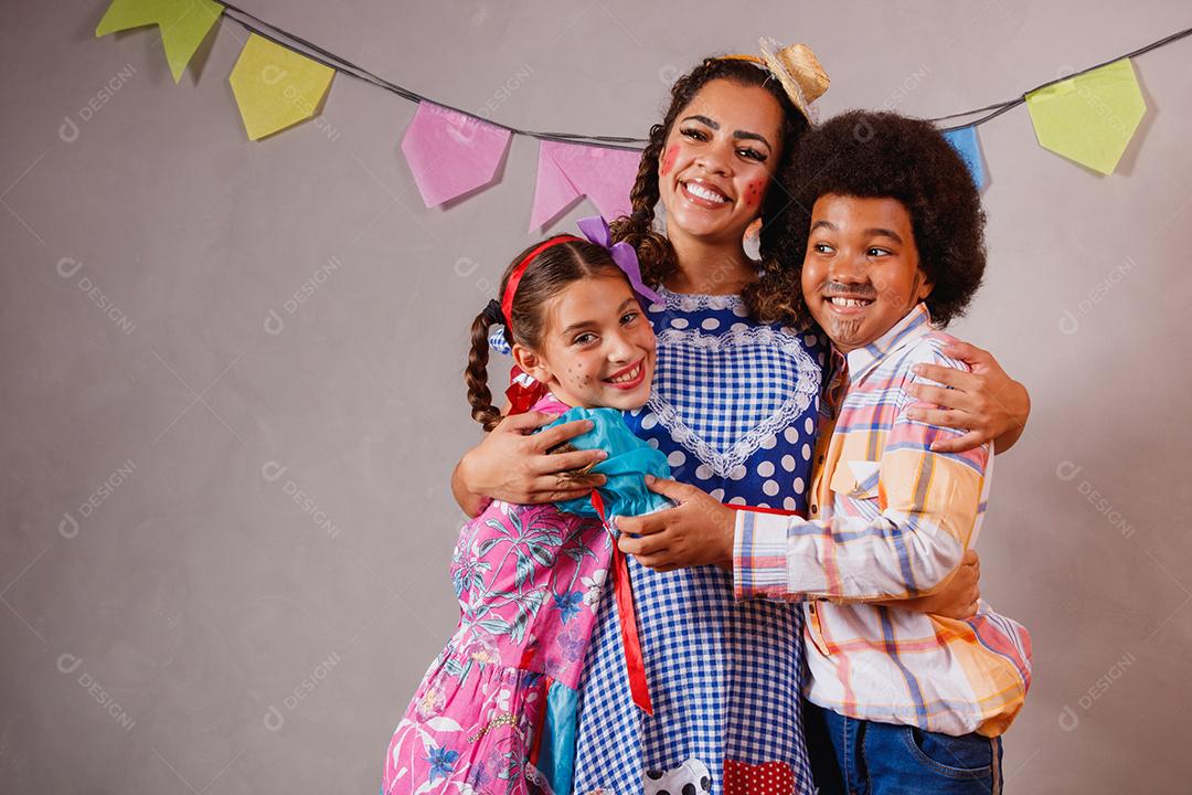 Mulher adulta e crianças vestidas para festa junina