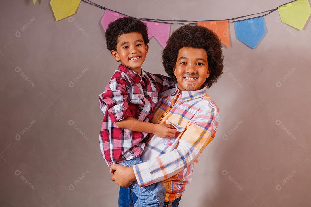 Irmãos afro vestidos com roupas de festa junina