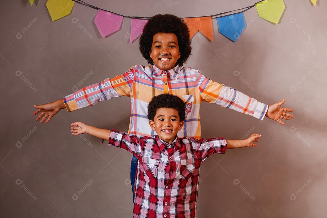 Irmãos afro vestidos com roupas de festa junina