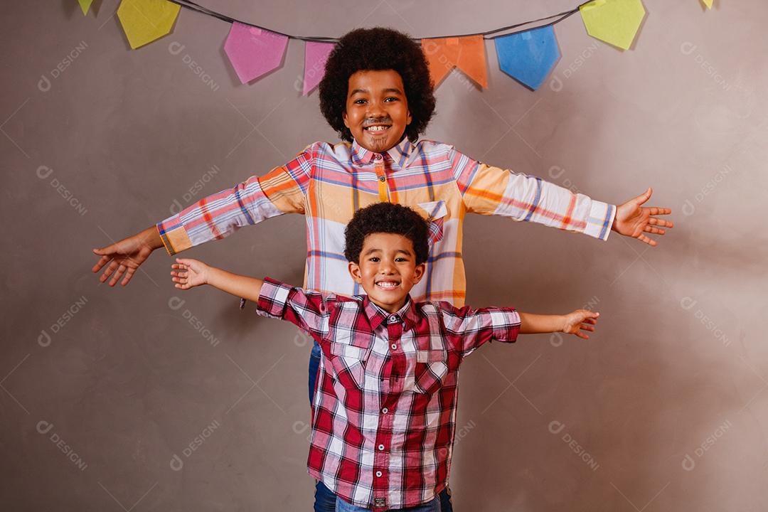 Irmãos afro vestidos com roupas de festa junina