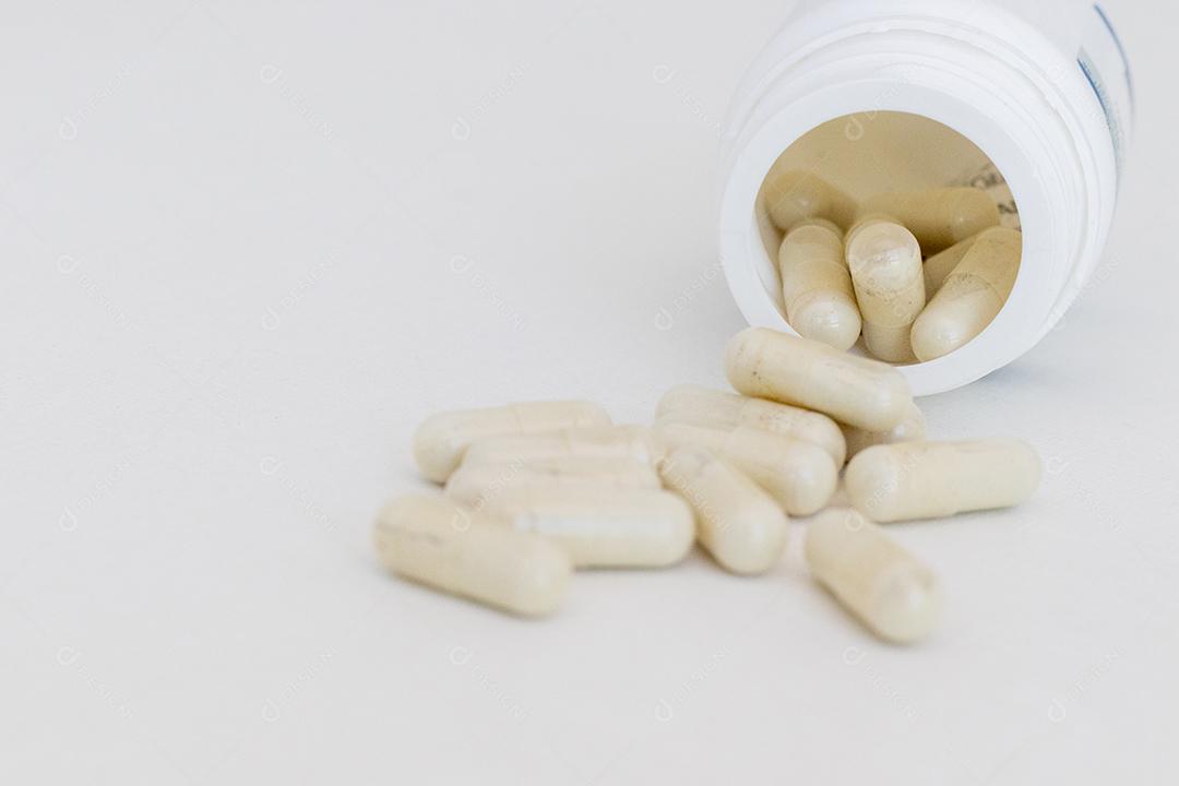 Frasco de remédios deramado sobre mesa branca