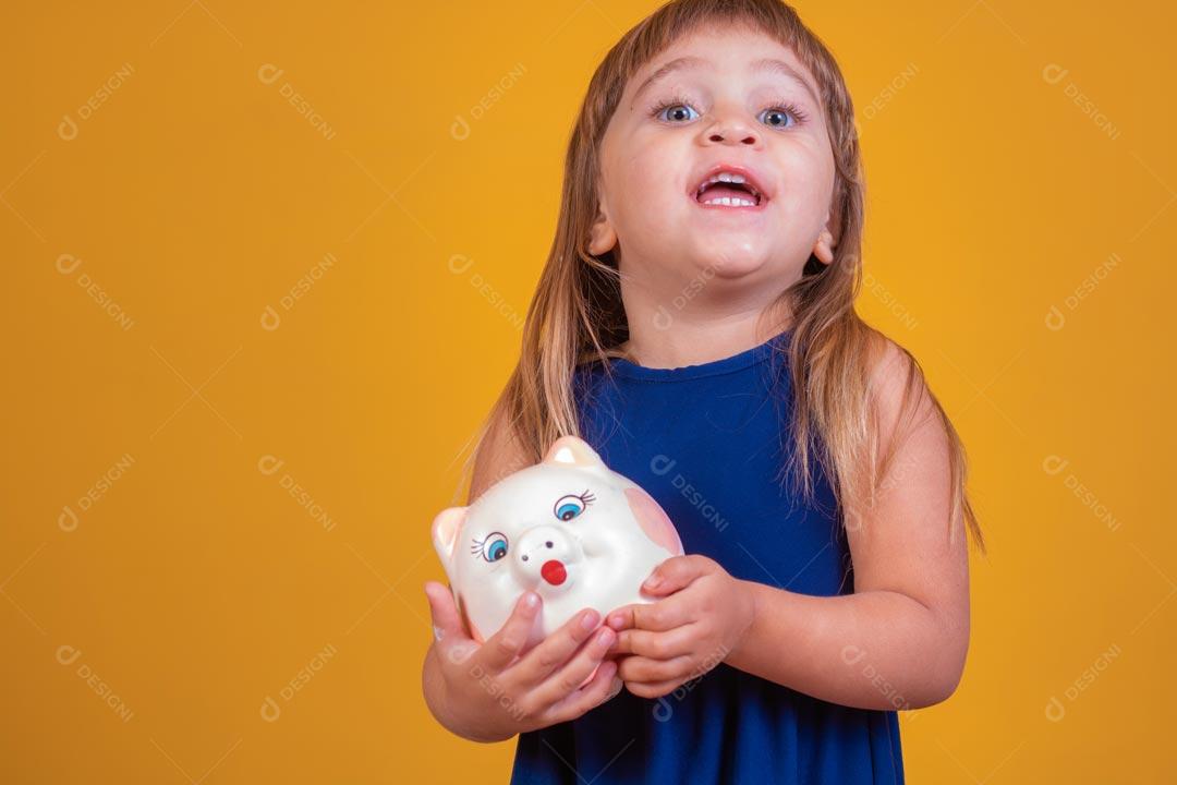 Menina loira com olhos azuis Expressão De Feliz Segurando Cofrinho De Porco