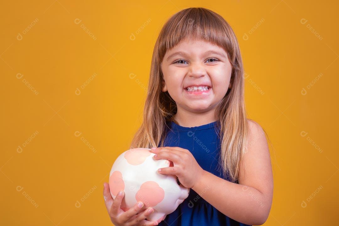 Menina loira com olhos azuis Expressão De Feliz Segurando Cofrinho De Porco