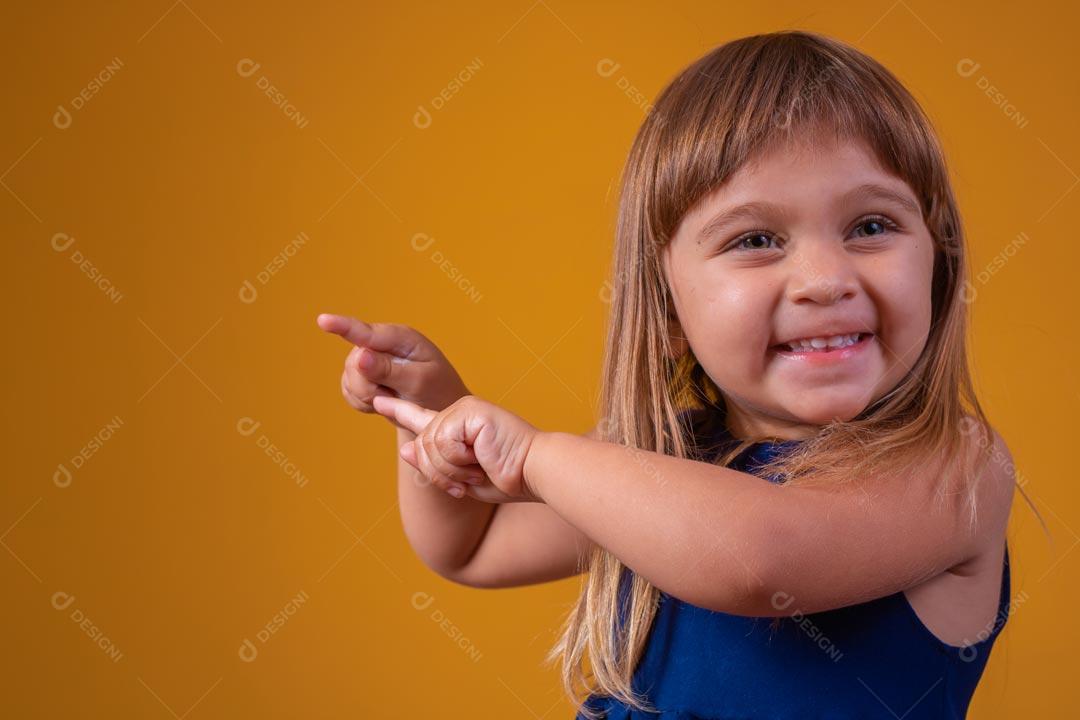 Menina loira com olhos azuis Expressão De Feliz Segurando Cofrinho De Apontando Para O Lado