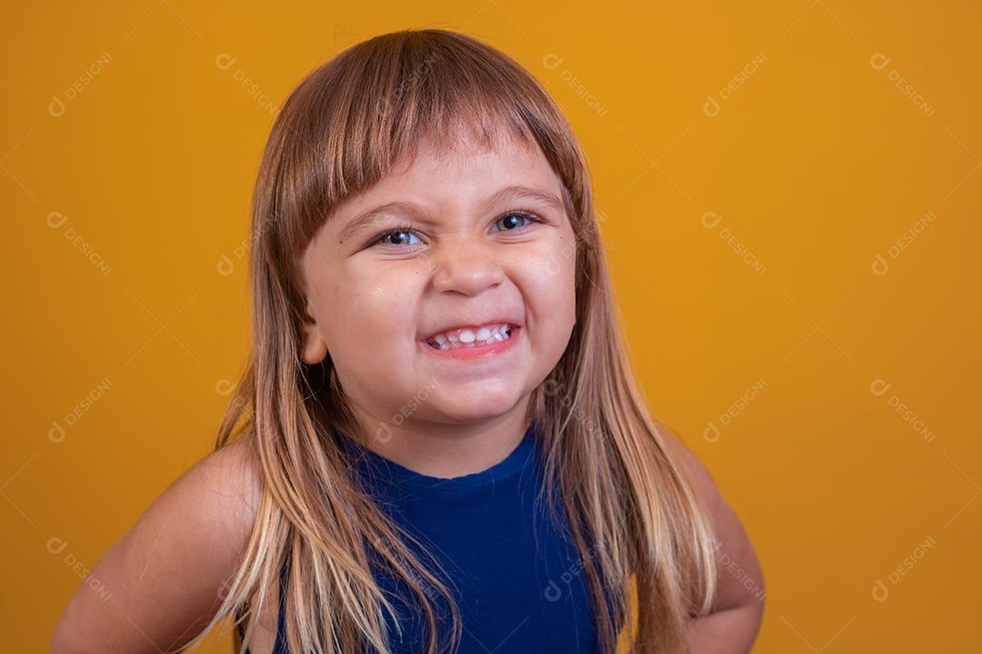Linda menina loira sorrindo olhando para a câmera em amarelo