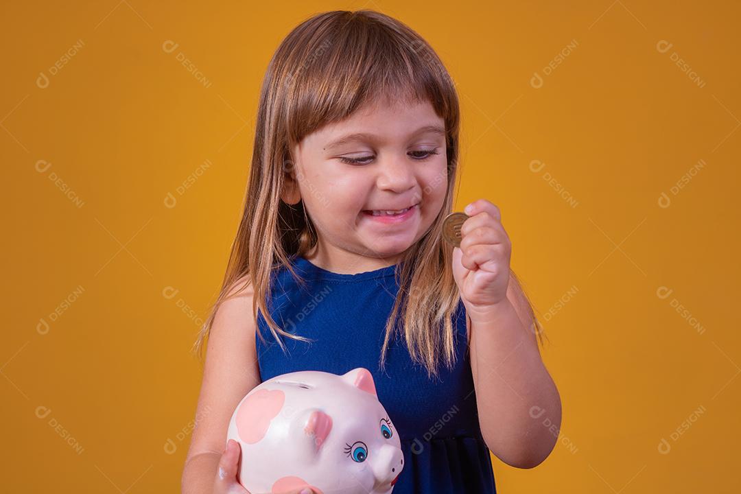 Criança pequena com cofrinho em fundo amarelo