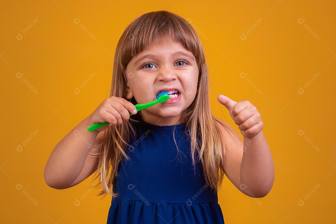 menina escovando os dentes e polegares para cima