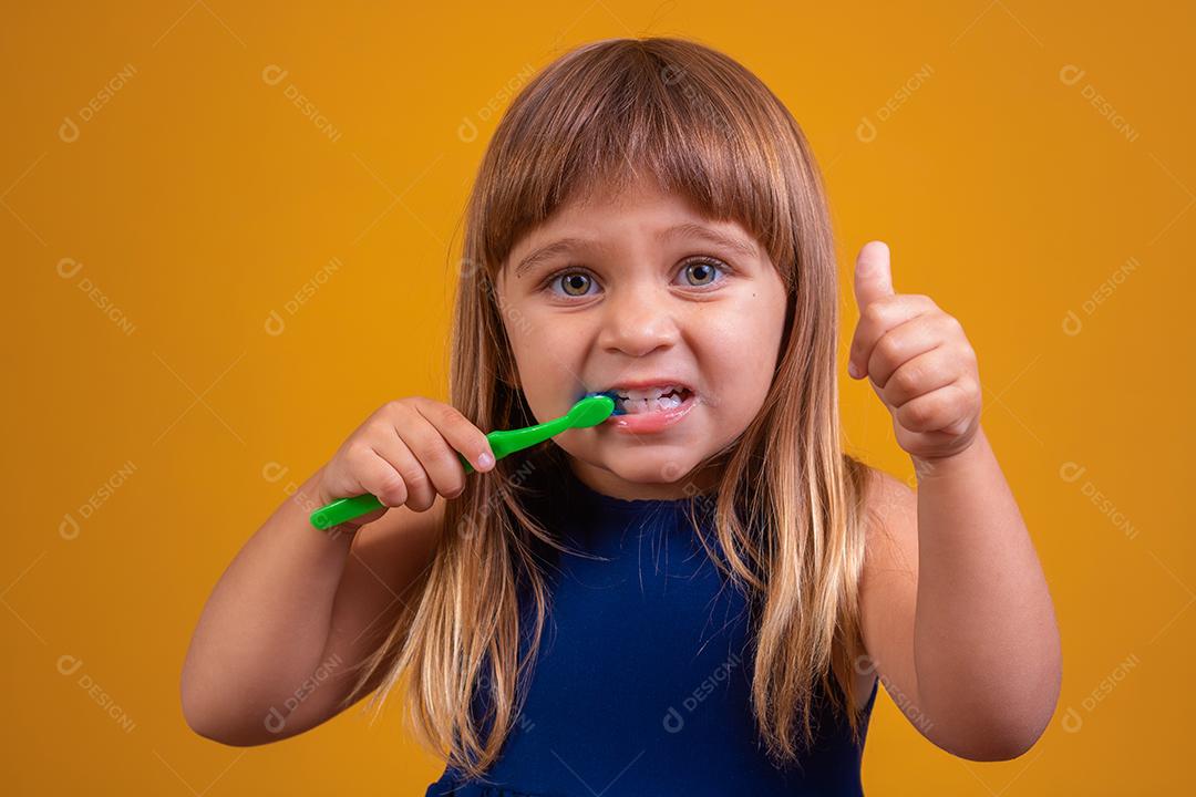 menina escovando os dentes e polegares para cima