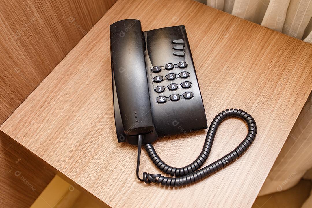 Telefone vintage preto em uma mesa marrom no hotel.