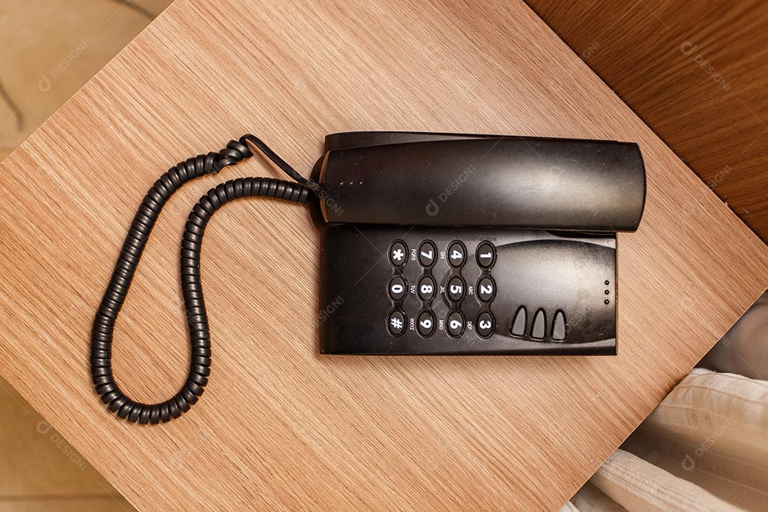Telefone vintage preto em uma mesa marrom no hotel.