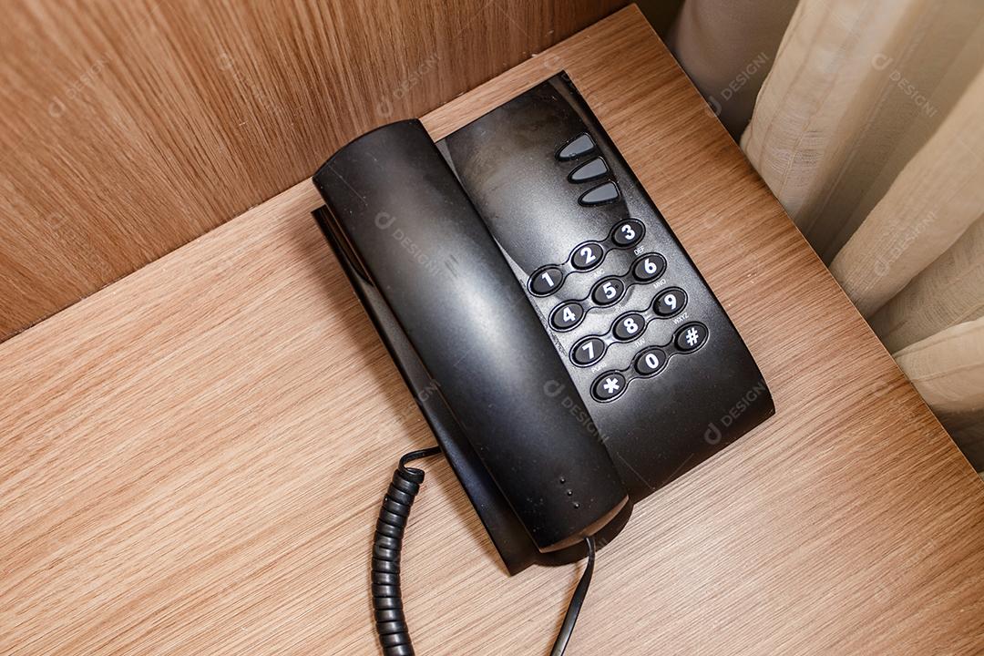 Telefone vintage preto em uma mesa marrom no hotel.