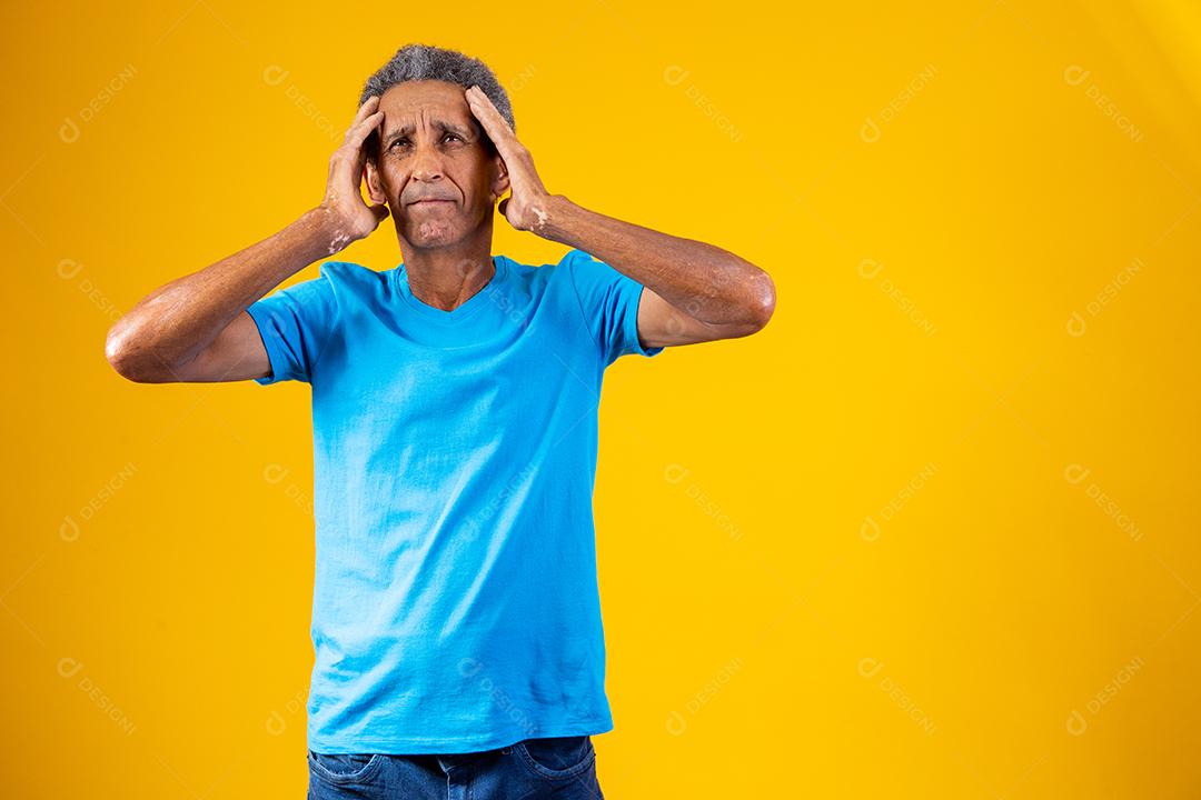 Homem idoso com expressão de dor em fundo amarelo