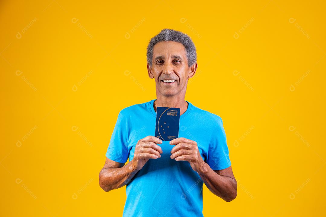 Homem idoso segurando carteira de trabalho em fundo amarelo