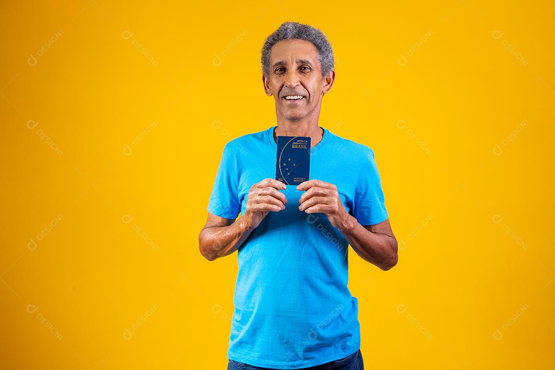 Homem idoso segurando carteira de trabalho em fundo amarelo