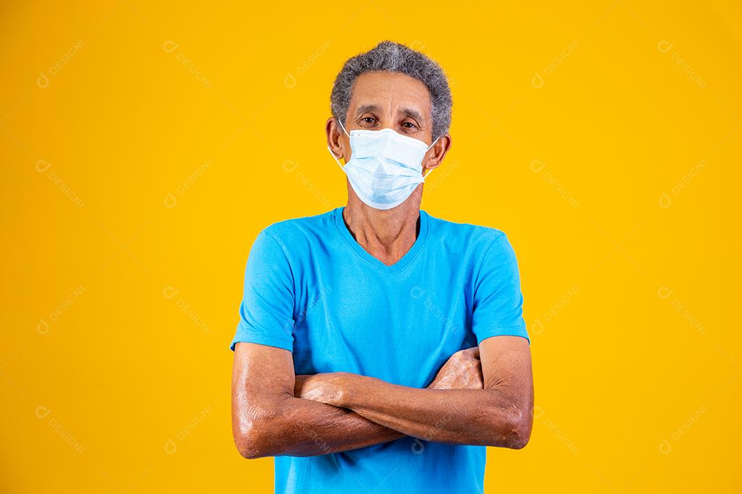 Homem idoso usando mascara branca em fundo amarelo