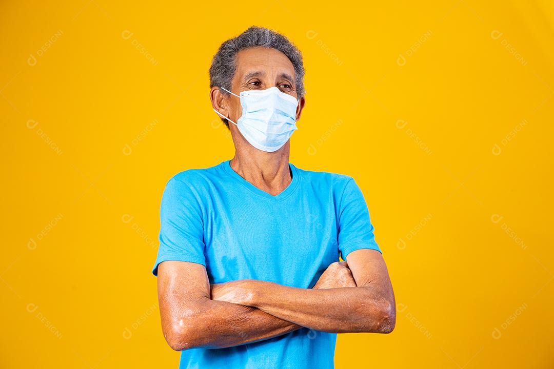 Homem idoso usando mascara branca em fundo amarelo